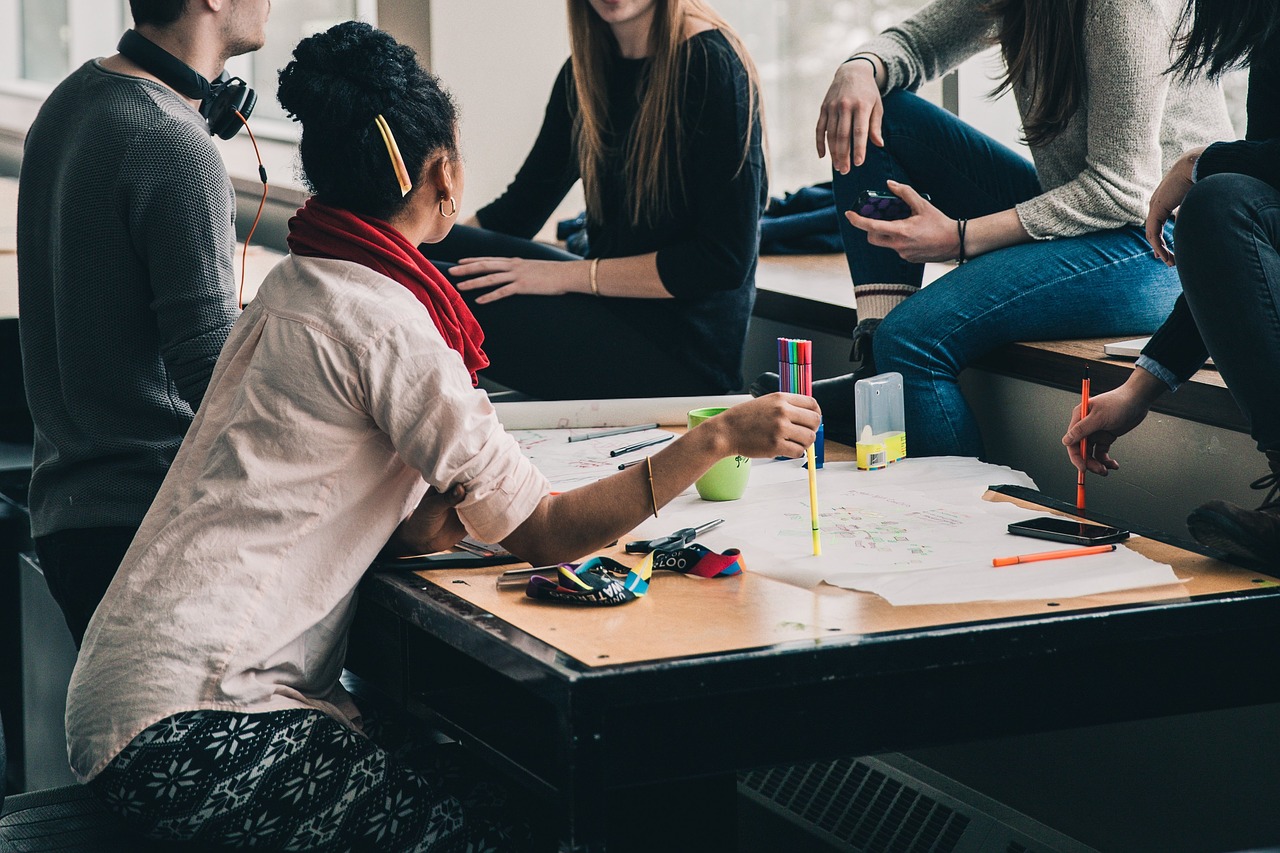 A group of people sitting around a desk with paper and highlighter having a discussion