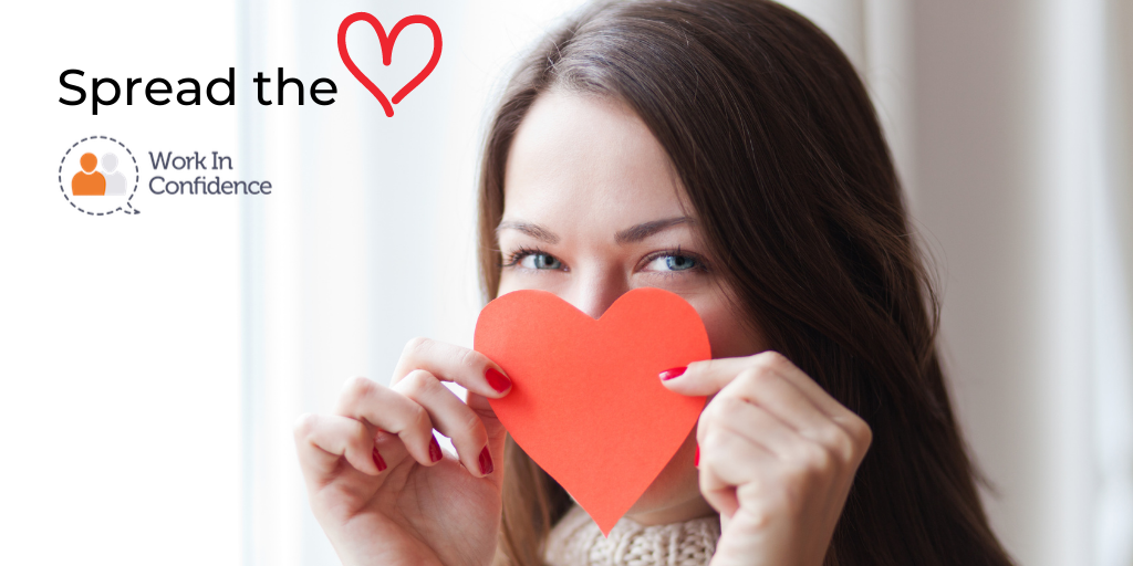 A white women holding a red heart in front of her nose and mouth and the text "spread the love"