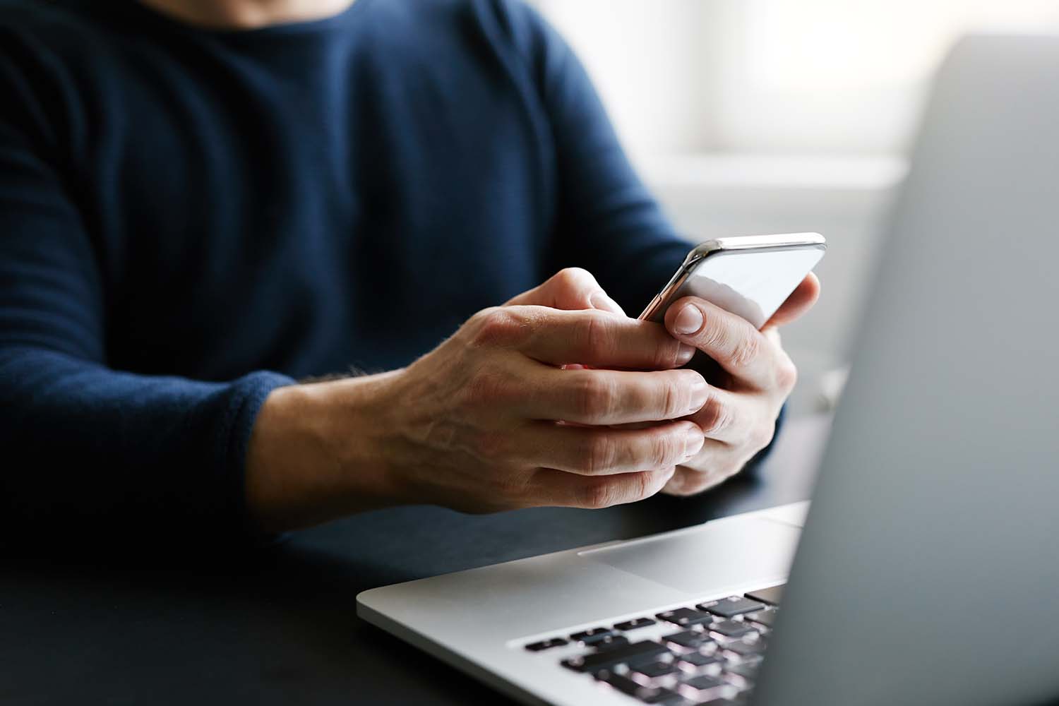 Man with mobile phone and laptop in office