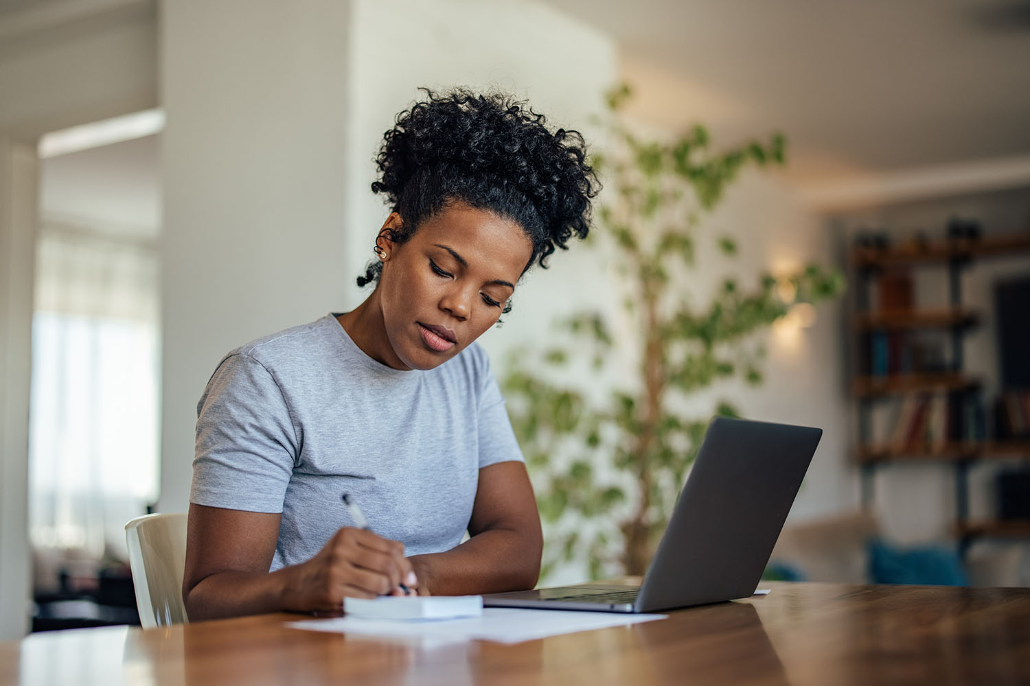 Hardworking african-american woman, writing a sketch of her resume